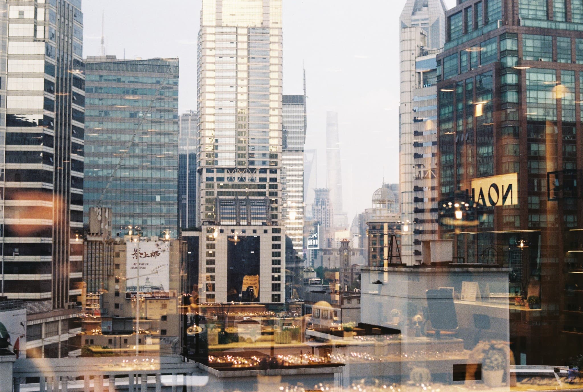 A view of a dense city skyline featuring tall glass skyscrapers and reflections on a window pane.