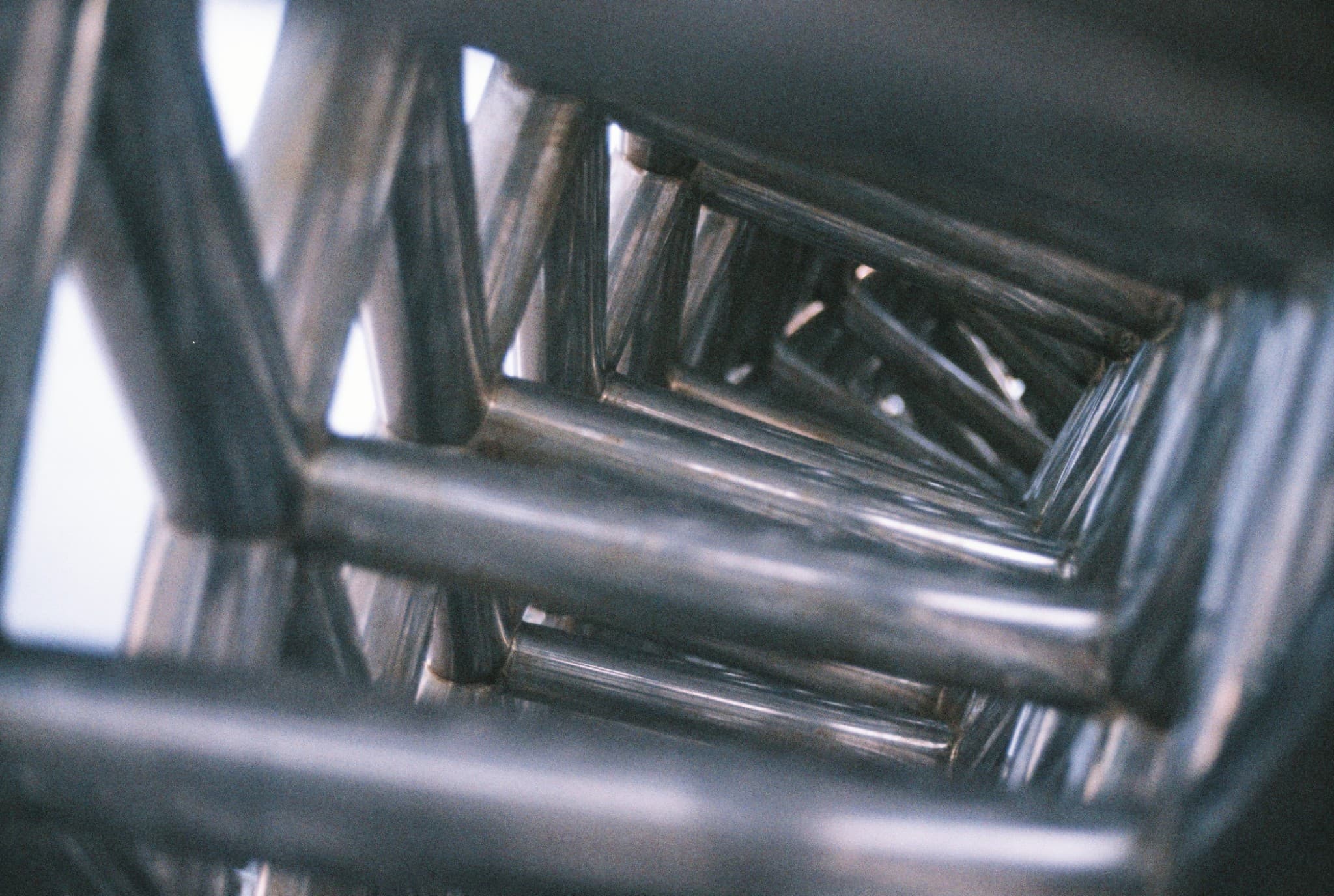 This photo shows a close-up view of metal tubes forming a truss structure, receding into the background.