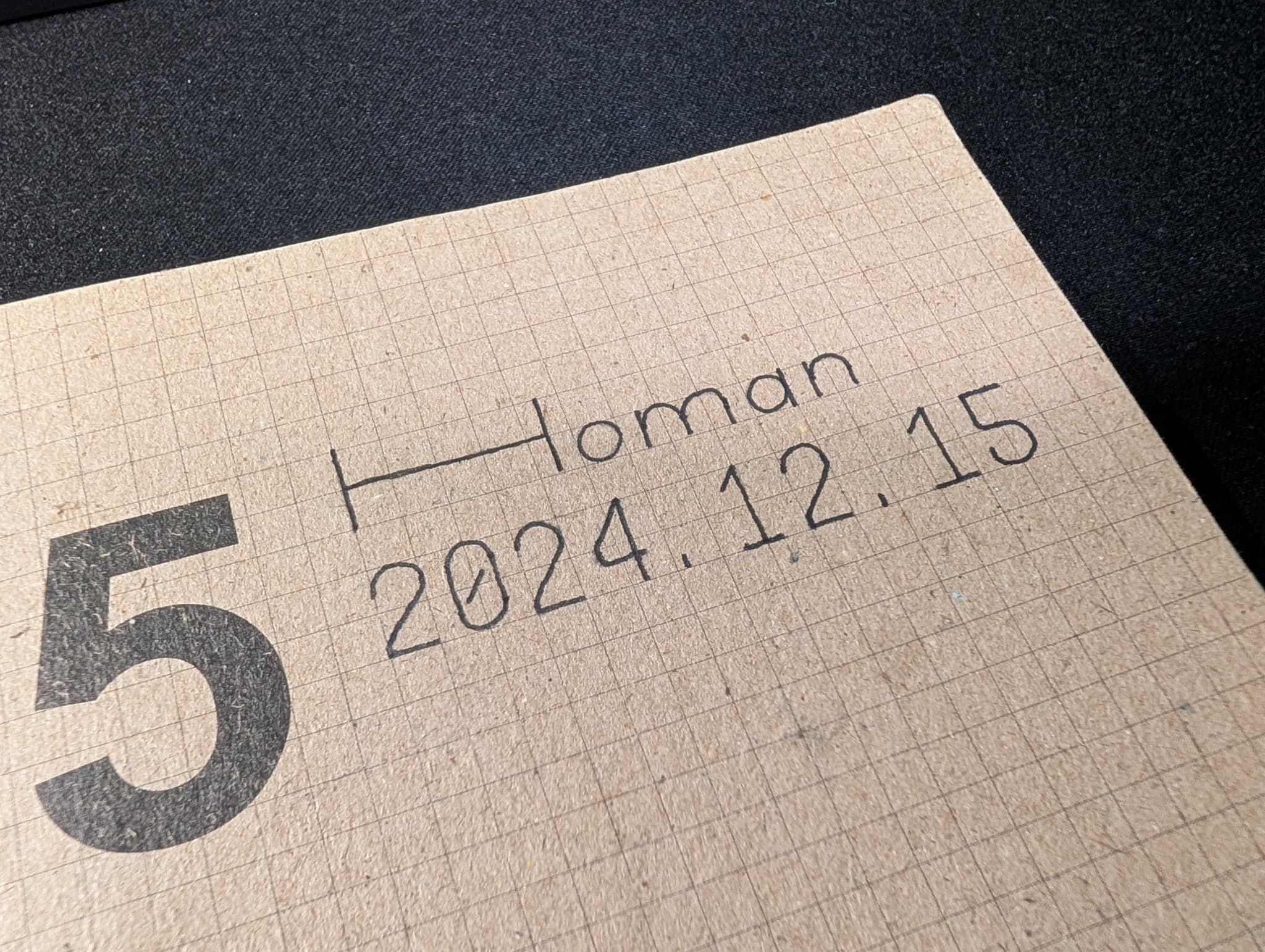 A close-up of a kraft paper planner page displaying a large number 5, the handwritten word Homan, and the date 2024.12.15.